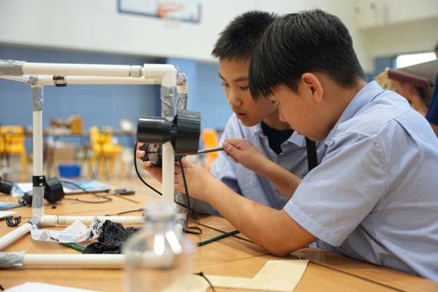Male students working together on robotics engineering challenge