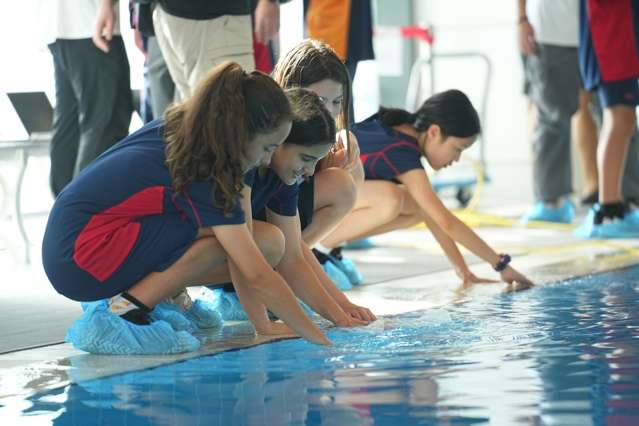Female students testing underwater robotics in swimming pool