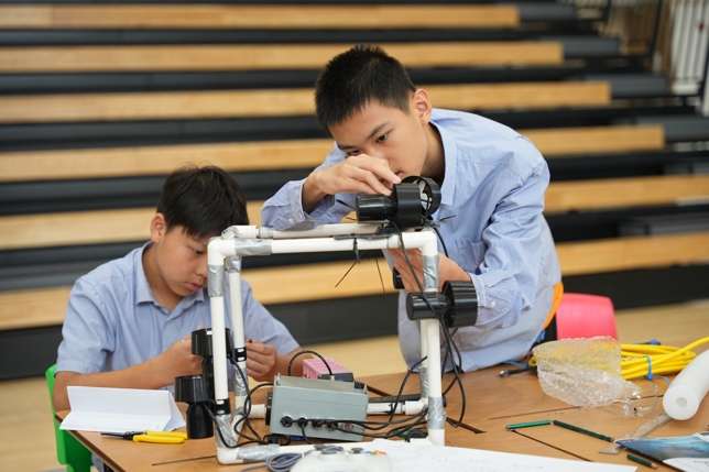 Male students operating underwater robotics presentation equipment