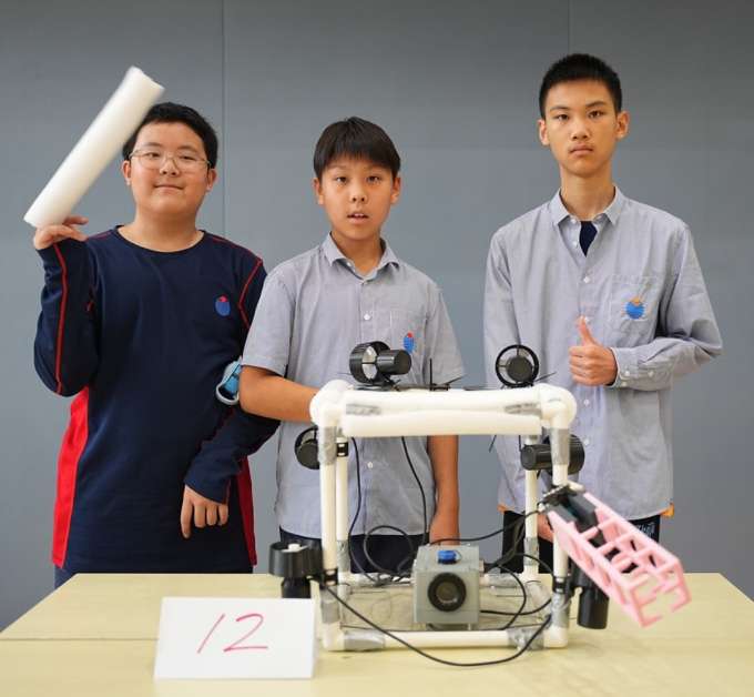 Male students presenting their underwater robotics innovation